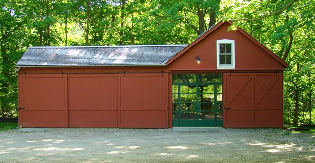 Red farm building with open door and windows - the studio at Weir Farm