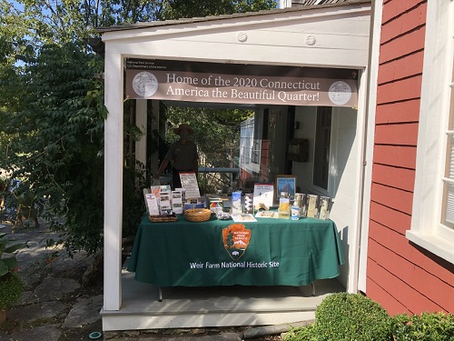 Park Ranger at Outdoor Visitor Center A park ranger behind a table on a porch filled with brochures and maps.
