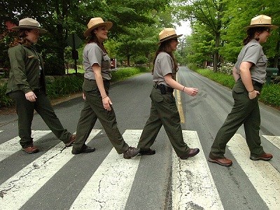 Four Park Rangers walking across a street on a crosswalk.