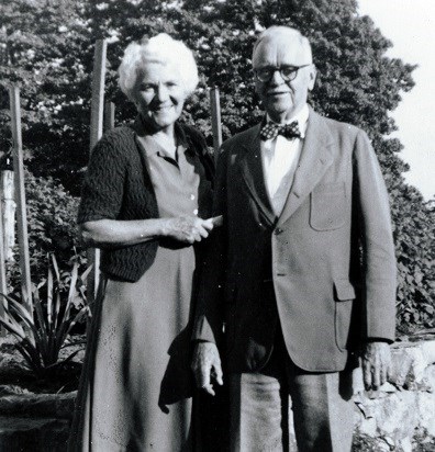 A black and white photo of a man and a women standing in a garden.