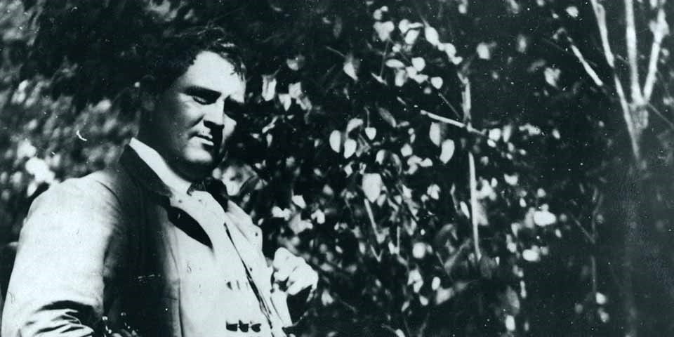A black and white photo of man with trees behind him