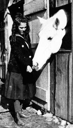 A black and white photo of a young girl feeding a horse.