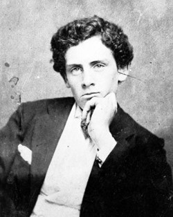 A black and white photo of a teenage boy sitting, resting head on his hand.