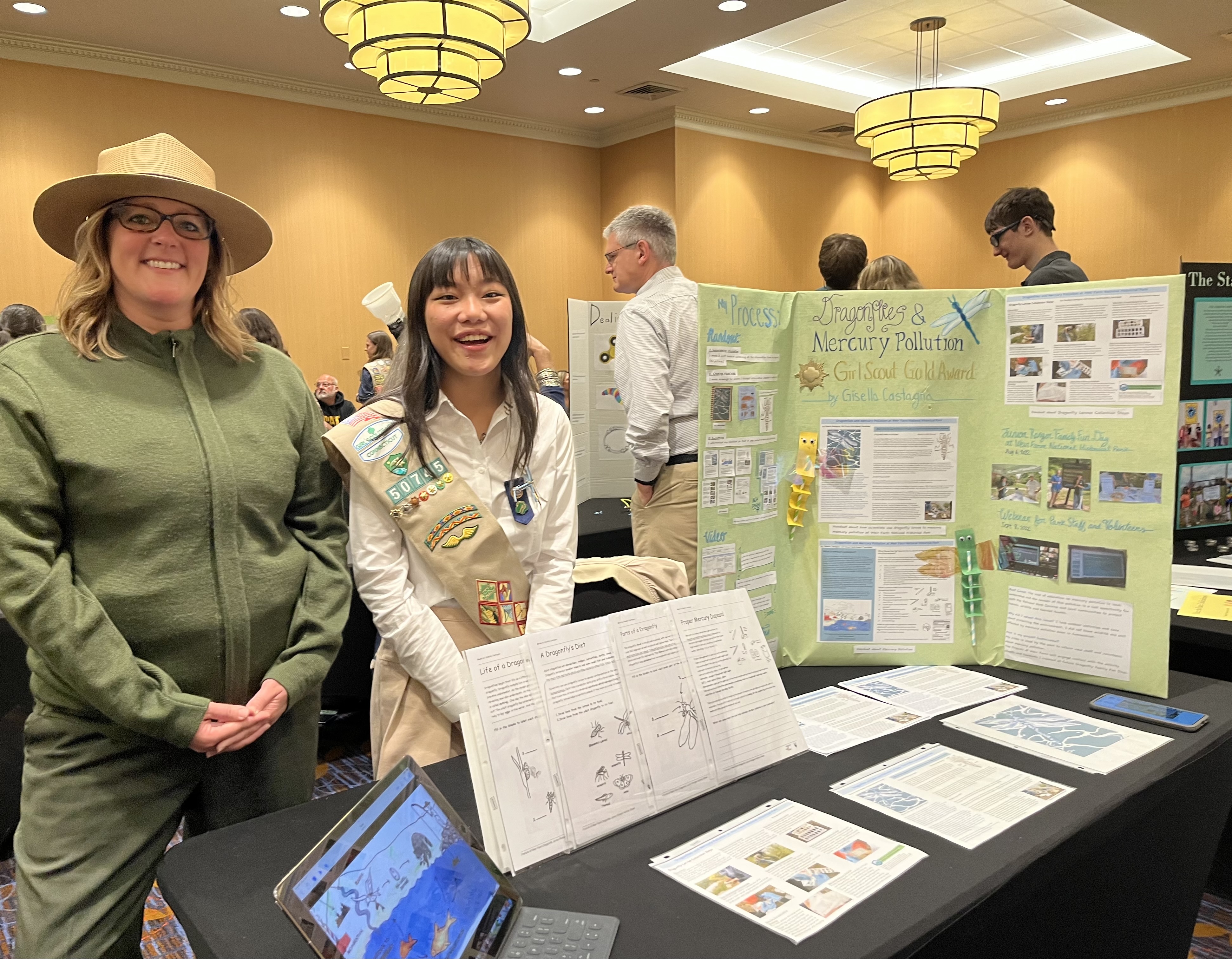 A Girl Scout and a park ranger at a table presenting research