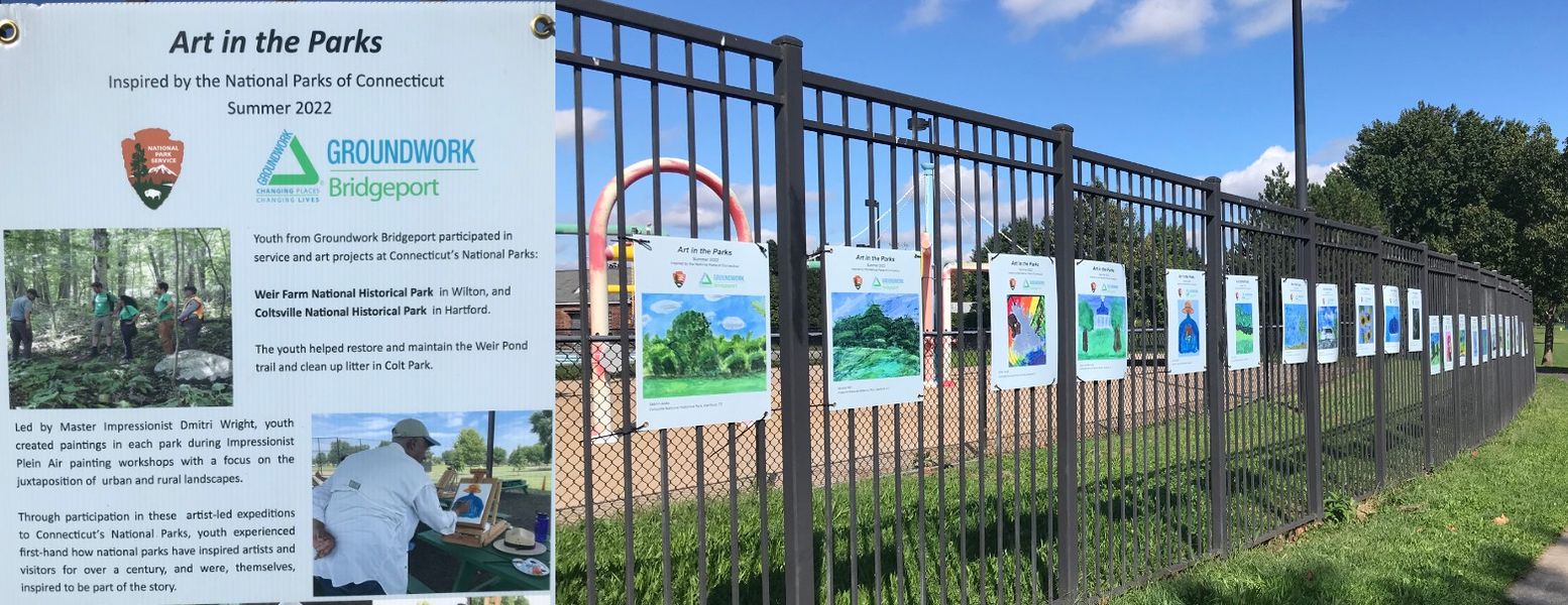 Several posters with artwork on it hanging on a black fence.