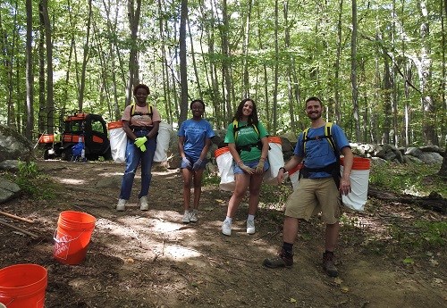 A group of four people cleaning up a trail.