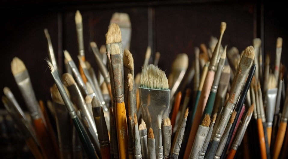 A bucket filled with different sized brushes.