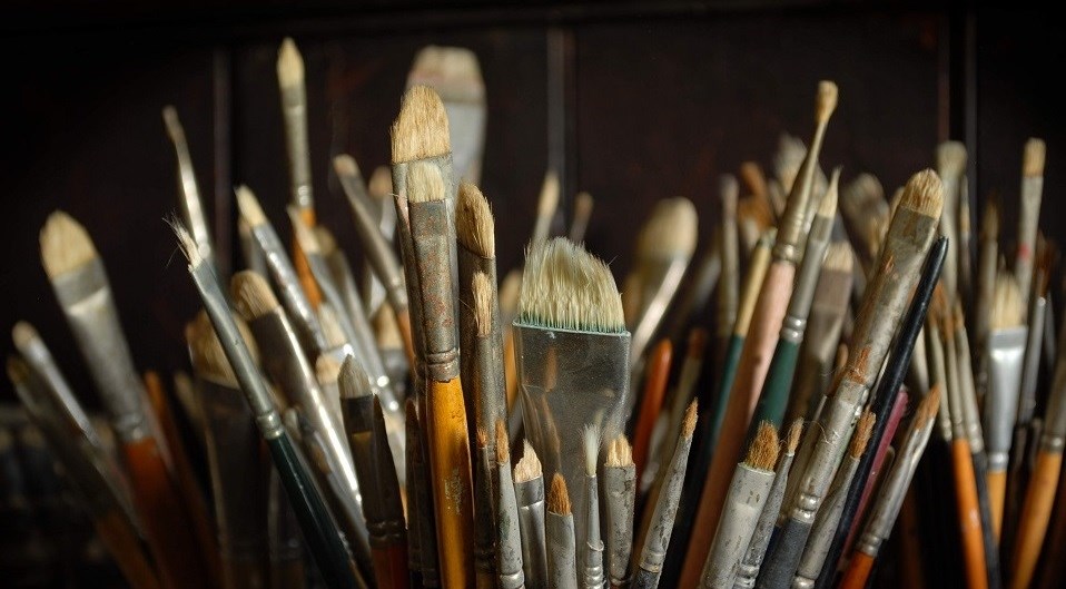 A bucket filled with different sized brushes.