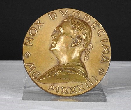 A bronze medal with a side portrait of man.