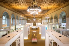 Modern exhibits are arrayed in a large room with an ornate ceiling and light fixtures Modern exhibits are arrayed in a large room with an ornate ceiling and light fixtures