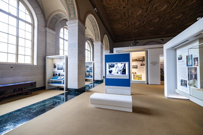 A bench in front of a video screen in an exhibit area surrounded by other informational panels.