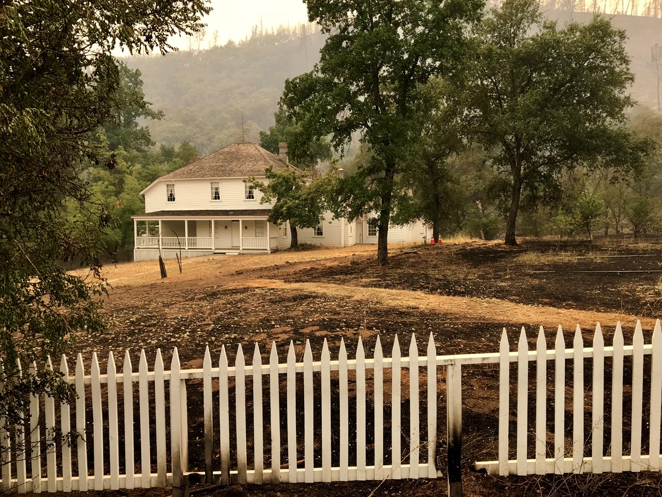 Camden House and front yard amidst smoky skies above. The house is painted white.