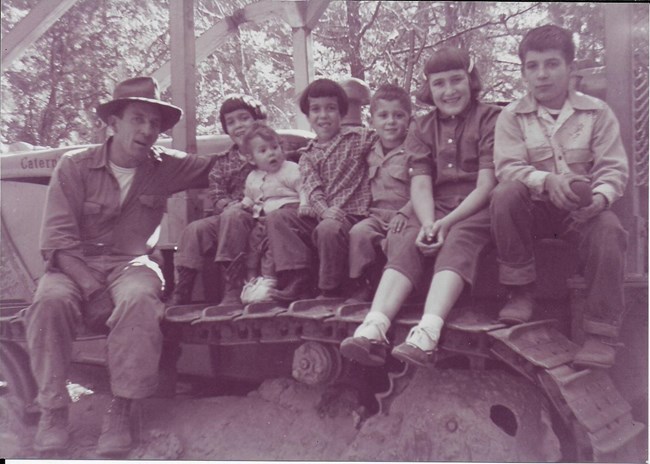 Clint Peltier and kids in 1955 near their horse barn. Black and white image.