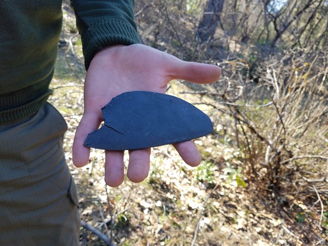 Park Archeologist John Fable holding up the partial sole of a female shoe at an archeology site.