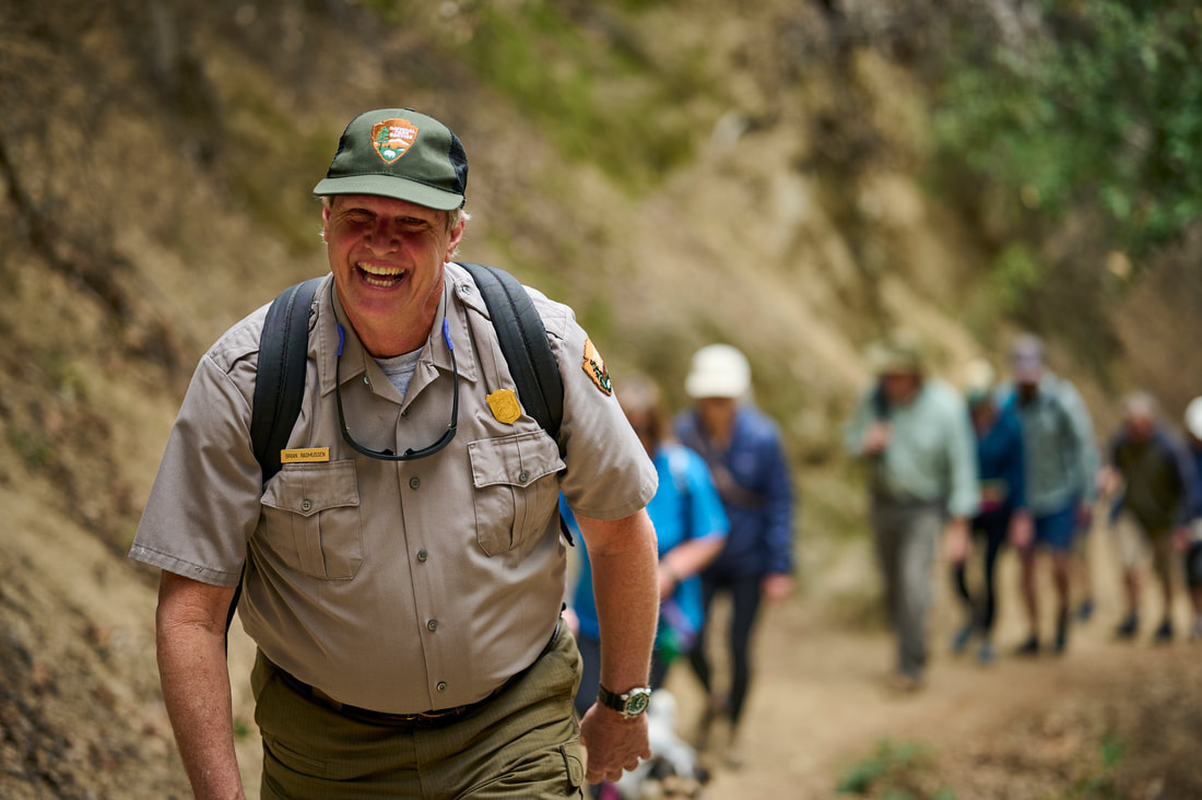 A park ranger leads a hike for a group of visitors. A park ranger leads a hike for a group of visitors.
