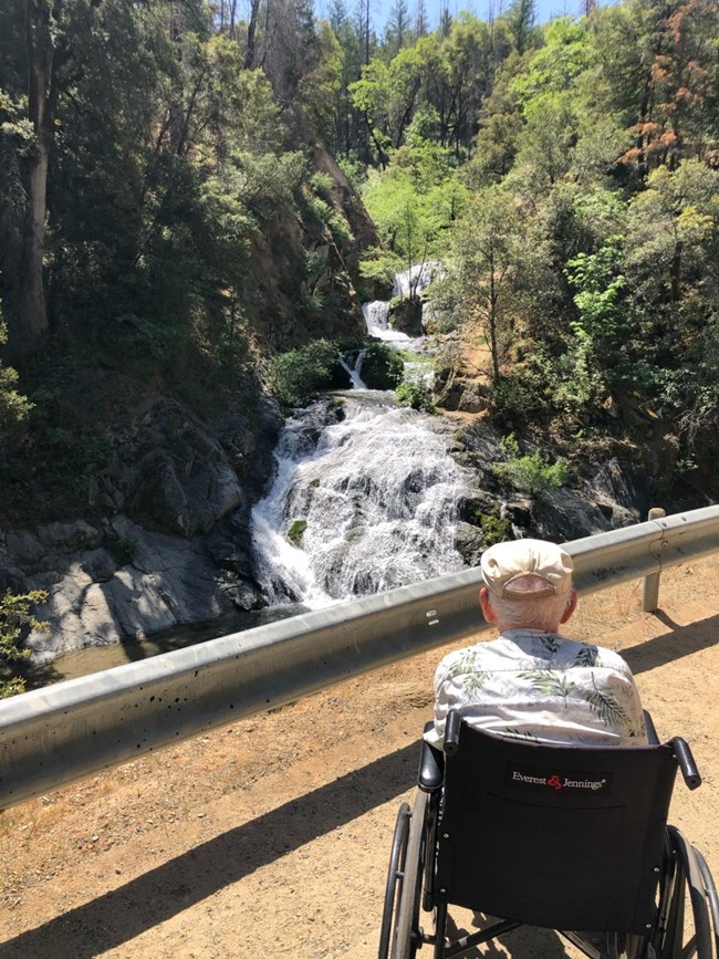 A 97-year-old man in wheelchair enjoying the view of Crystal Creek Falls at the end of the paved trail.