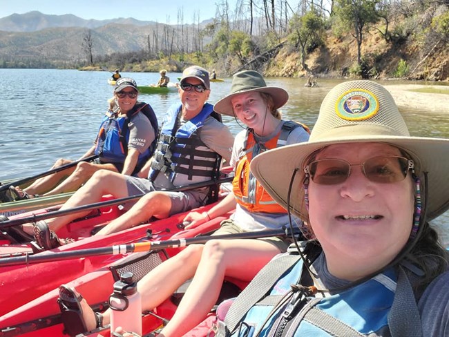 Park volunteers and staff on kayaks on lake are all smiles.