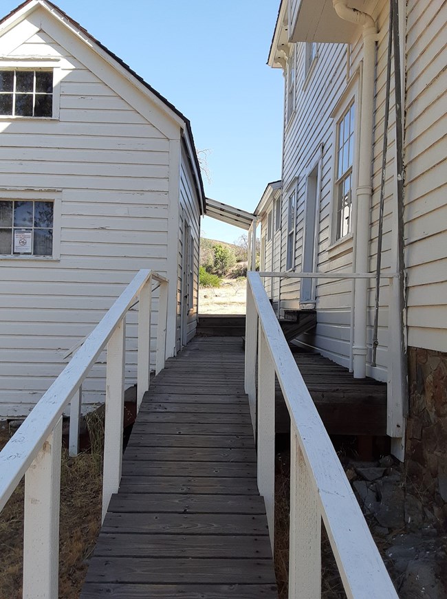 Back deck of white Camden House. Wooden house and outbuildings.