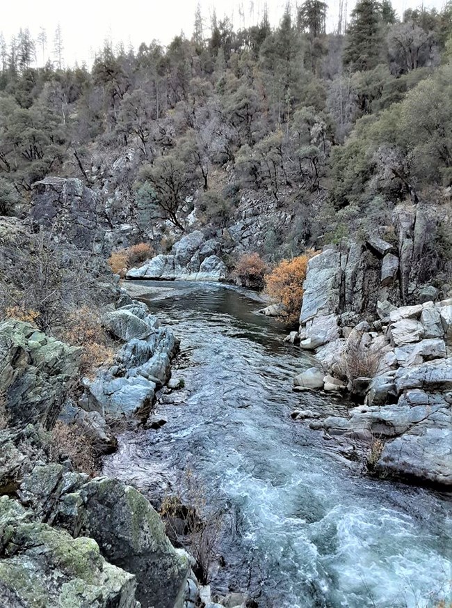 Clear Creek Canyon near Guardian Rock. The creek is showing whitewater and the creek banks are rugged with large boulders.