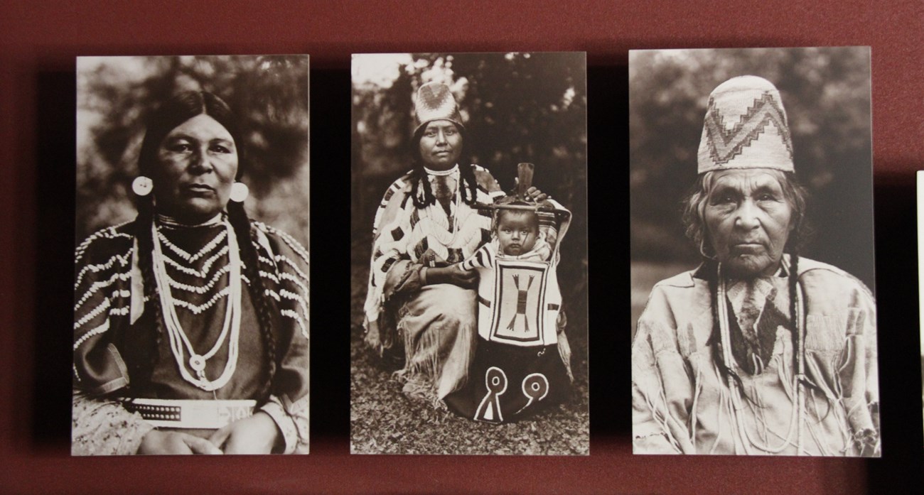 Three black and white photos of Cayuse women mounted on a red wall side by side