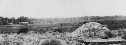 Dirt mound in foreground. House can be seen in background. Dirt mound in foreground. House can be seen in background.