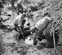 Workers remove mill stone from dig site.