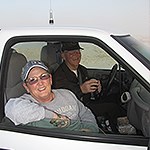 Two Volunteers smile from inside a vehicle
