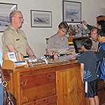 Volunteers stand behind desk in visitor center and answer visitor questions