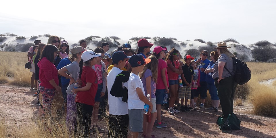 A rangers stands in front of a group of children A rangers stands in front of a group of children