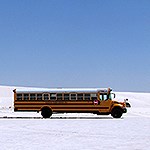 A bus parked on white sand under blue sky