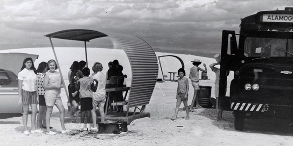 Black and white image of girls by a school bus and picnic tables. Black and white image of girls by a school bus and picnic tables.