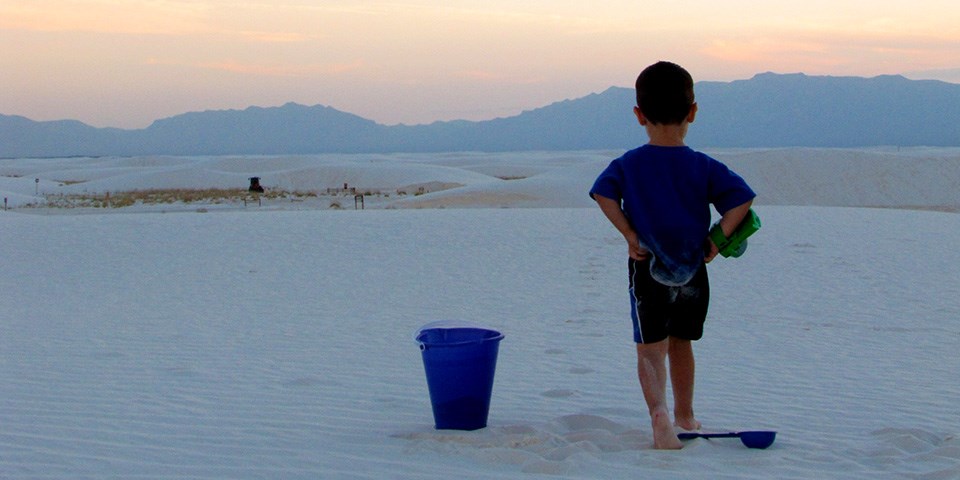 Child playing in the dunes with a sunset on the background. Child playing in the dunes with a sunset on the background.