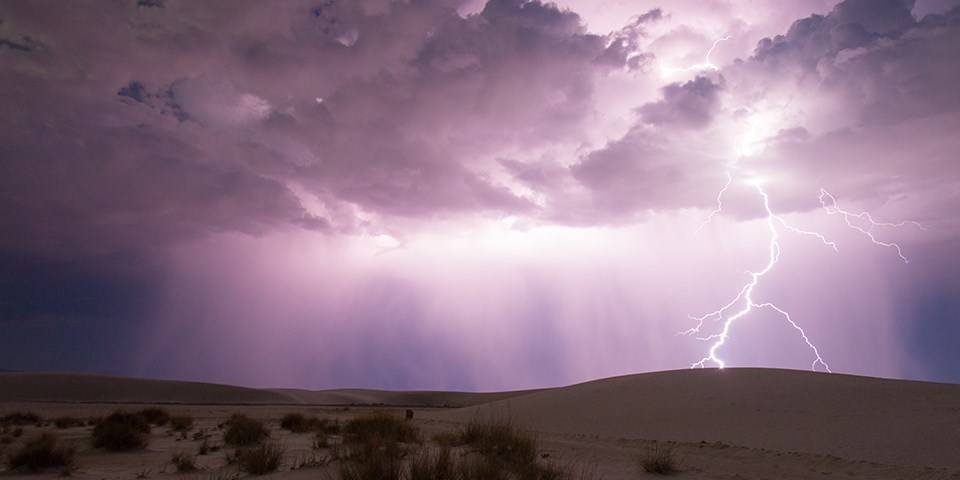 Lightning strikes amidst a bright purple sky and white sand dunes Lightning strikes amidst a bright purple sky and white sand dunes