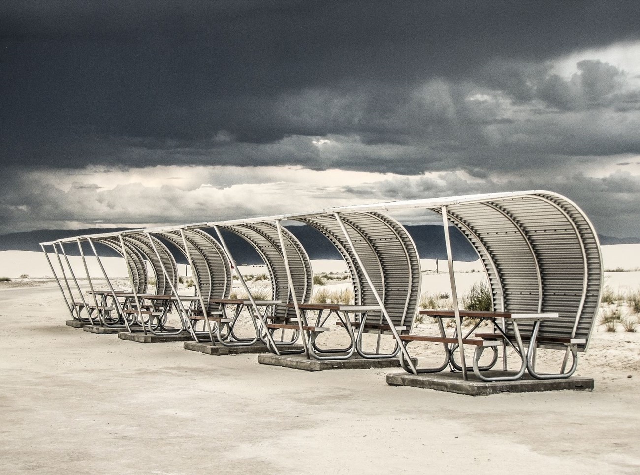a curved metal structure covers picnic table on a concrete pad.
