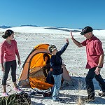 A family with a yellow tent on white sand