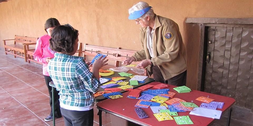 Visitors engaging with a volunteer for a crafty kids program.