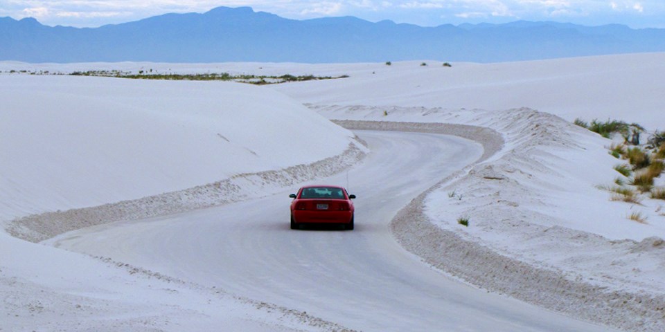 Red car driving part of Dunes Drive.