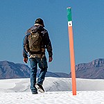 Visitor hiking in the dunefield with the San Andres Mountains on the background.