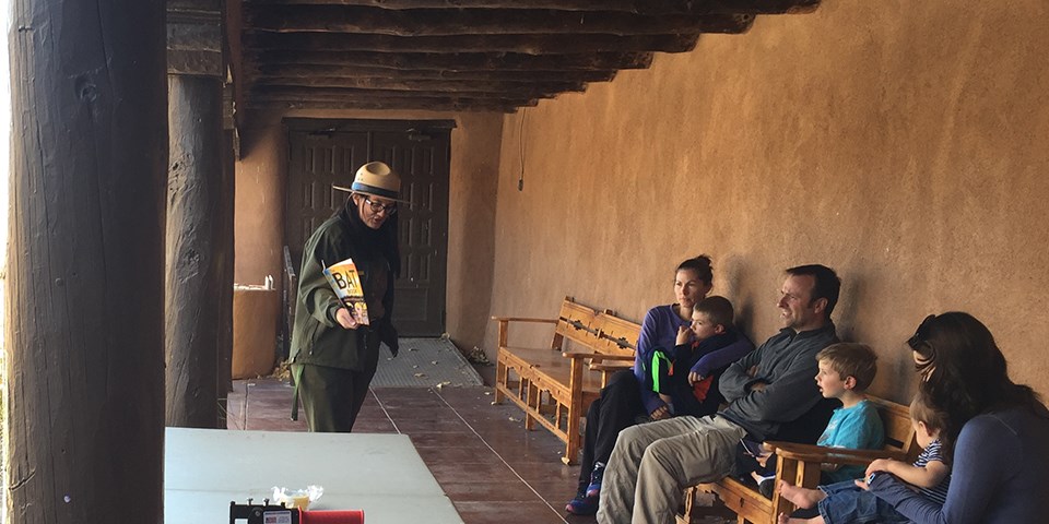 Ranger holding picture in hand showing visitors sitting on benches. Ranger holding picture in hand showing visitors sitting on benches.