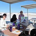 Three people eating at a picnic table