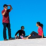 One man standing and two children sitting on a white sand dune