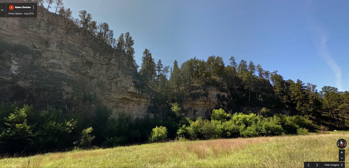 Rising limestone cliff above intermittent stream Rising limestone cliff above intermittent stream
