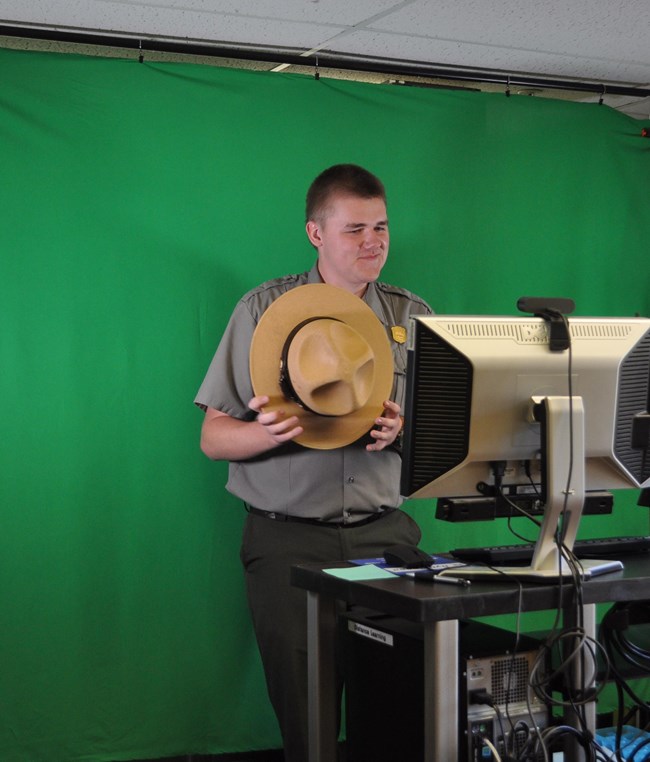 Ranger with Distance Learning Equipment Ranger holding their flat hat in a studio.