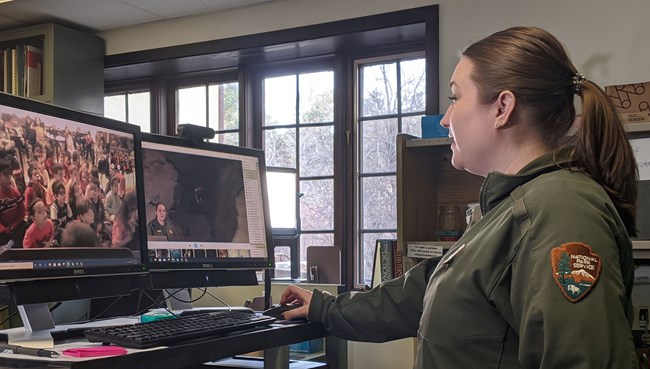 Ranger in front of two computer screens with students on a video call on the left.