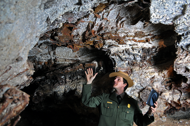 park ranger gesturing toward cave ceiling while holding an iPad park ranger gesturing toward cave ceiling while holding an iPad