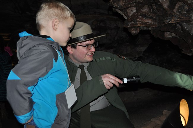 Park Guide Luke Howard with Nolan Humbracht Waiver on File Ranger and young boy looking at a feature in the cave.