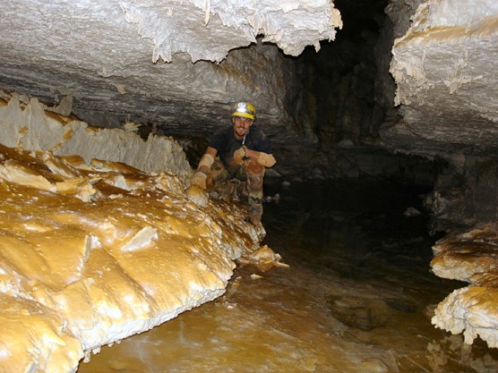 Cave explorer Carl Bern kneeling next to Lake Vega on a recent exploration trip in the southwest corner of the cave.