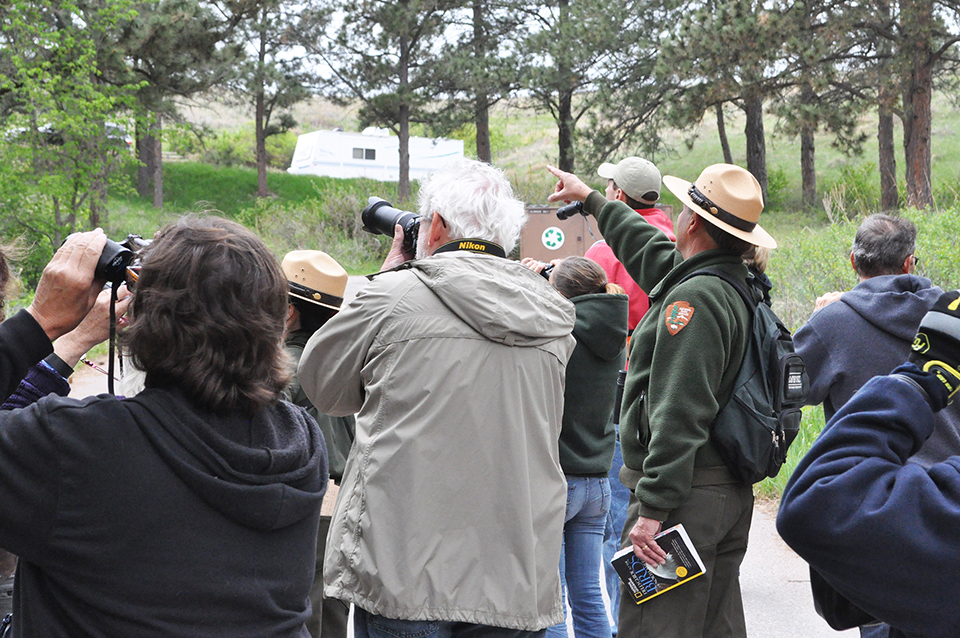 Group of people on a bird walk with a ranger pointing toward the left of the photo.