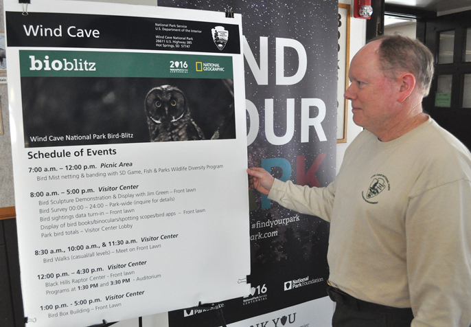 Dan Roddy standing in the visitor center next to a banner about the Bird Blitz.