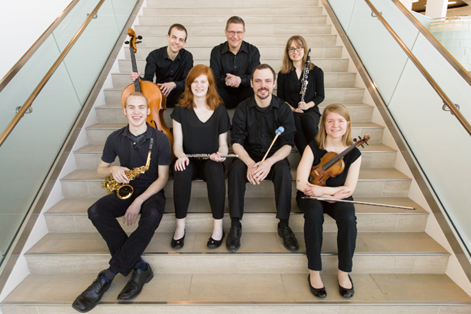 7 musicians with their instruments sitting on stairs.